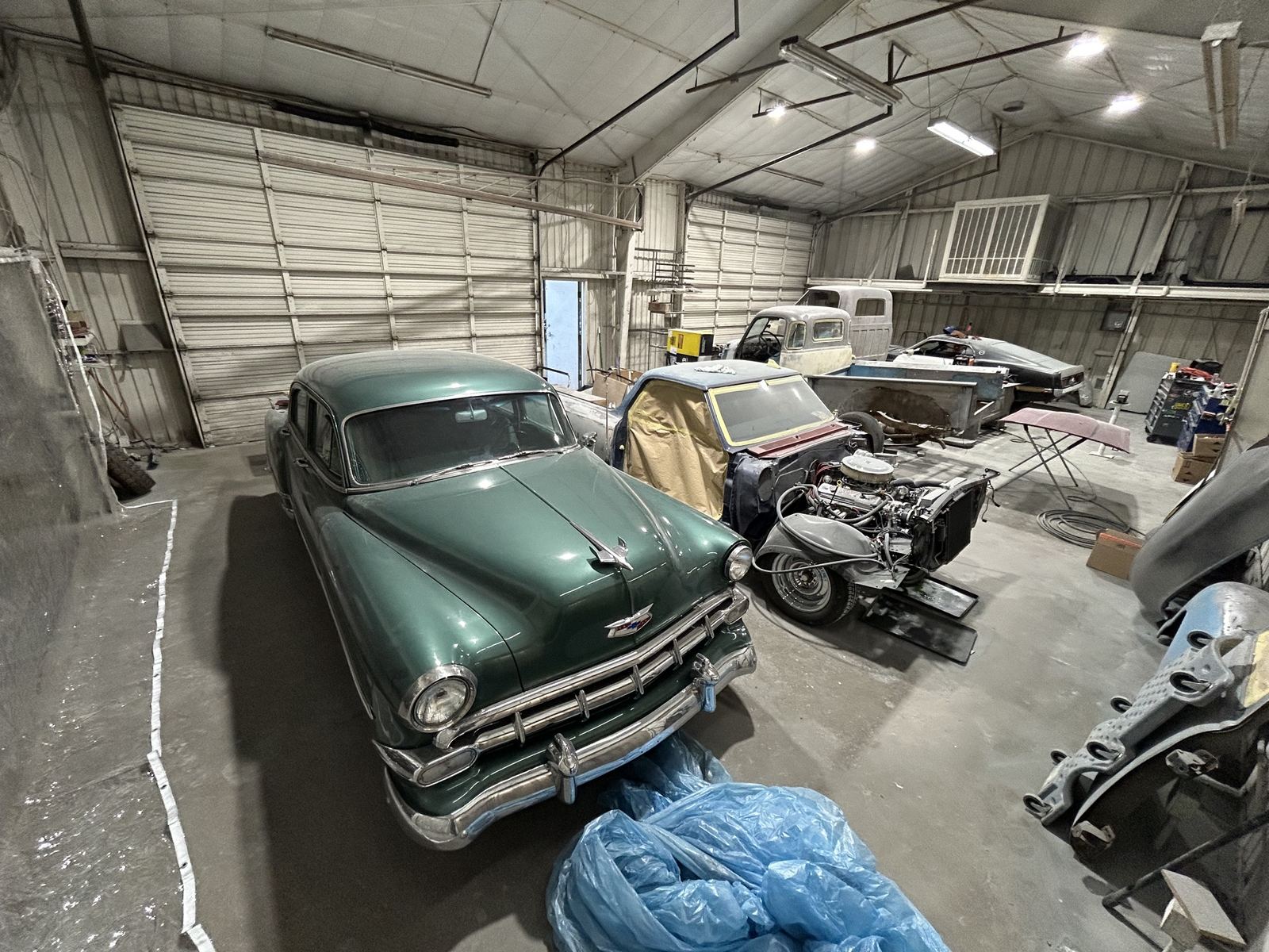 A green 1954 Chevrolet Bel Air and project cars inside the body shop
