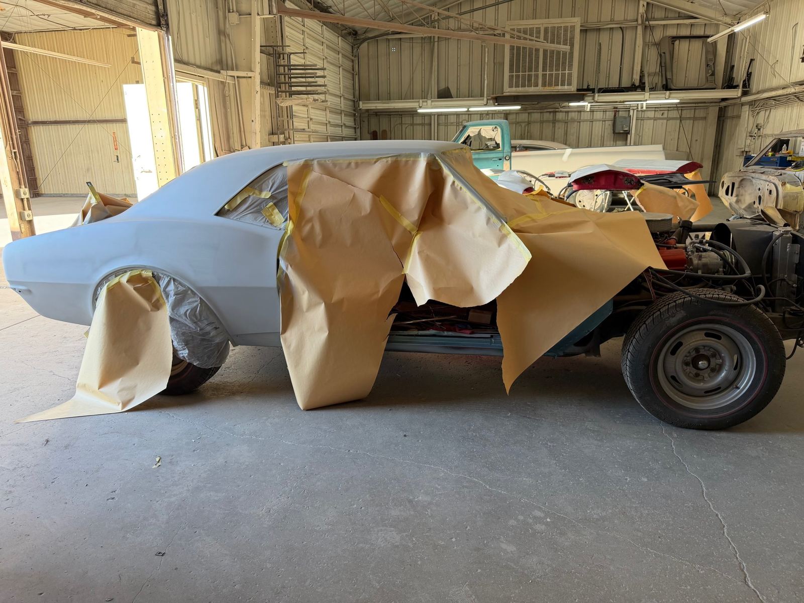 A first generation Camaro in primer, masked for paint