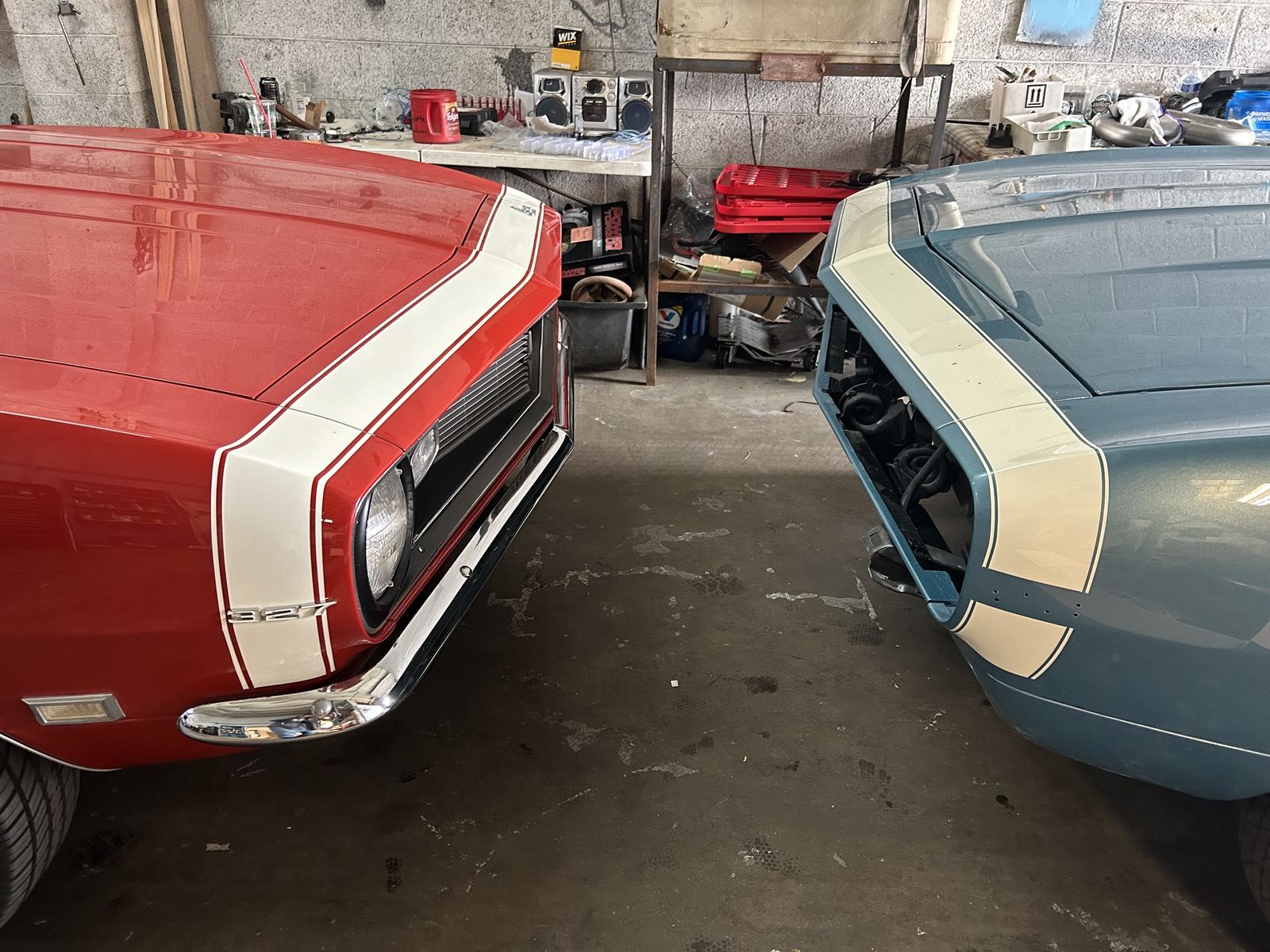 A red Camaro 327 and a blue Camaro with matching nose stripes