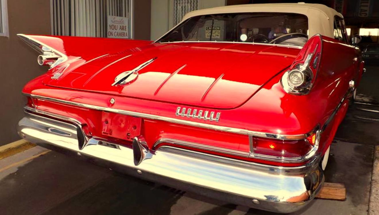 Tail fins of a red Chrysler convertible outside the shop
