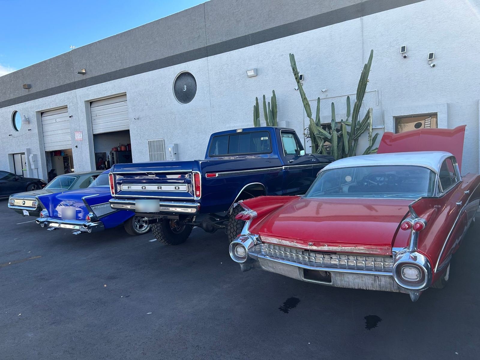 A 1957 Chevrolet, a Ford pickup and a 1959 Cadillac outside the Phoenix shop